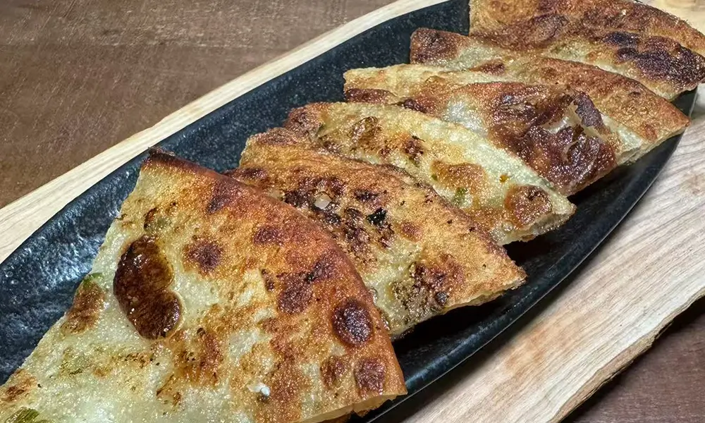 Crispy scallion pancakes served on a black platter at Sushi & Noodles a Japanese Restaurant in Brooklyn